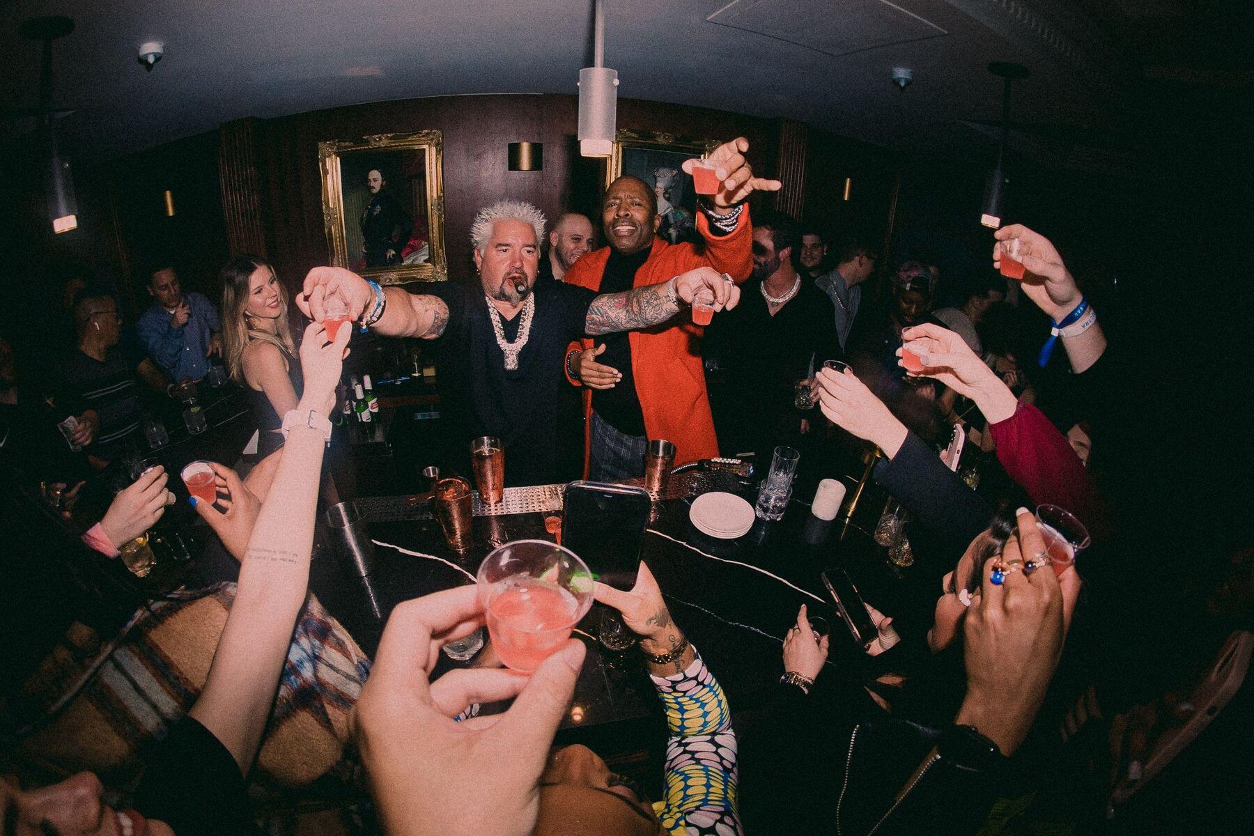 Guests raising glasses at a packed nightlife event